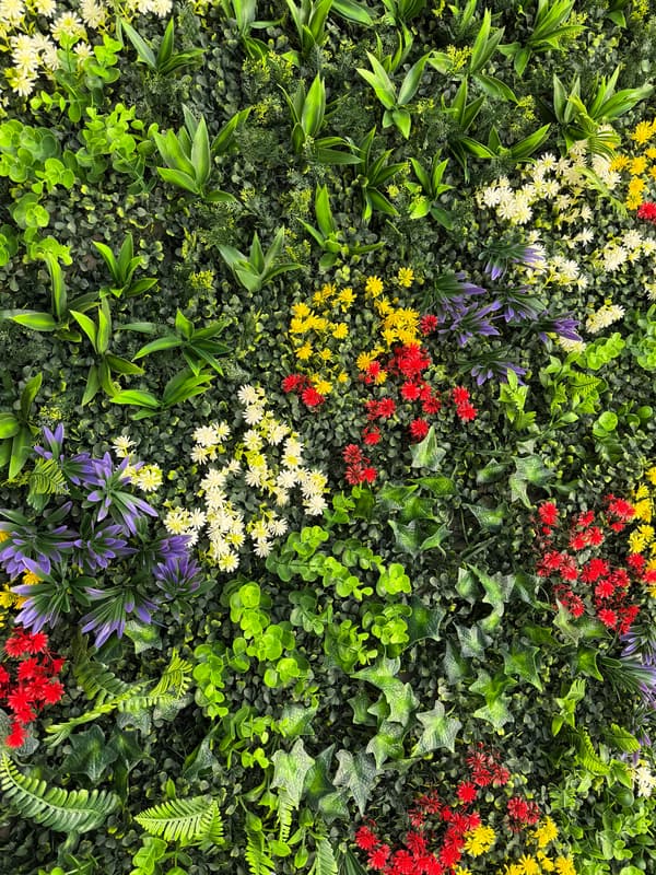 Detail view of cool tone artificial greenery wall panel highlighting mixed foliage textures and accent 