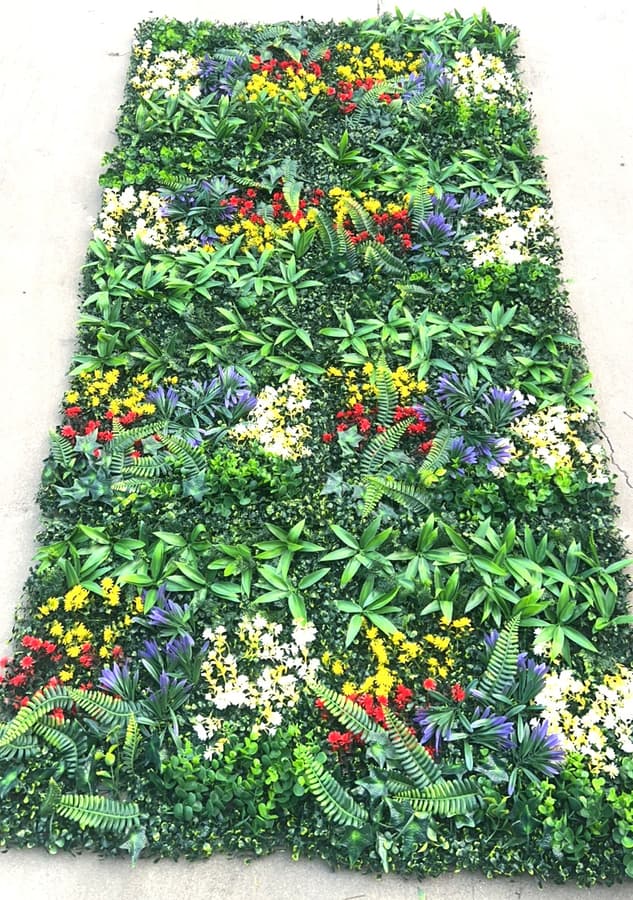 Multiple 20x20 artificial greenery wall panels connected to form a vibrant multi-tone foliage wall with leaf-based color variation