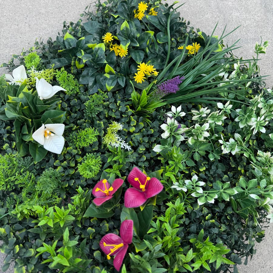 Close-up of floral artificial greenery wall panel showing layered foliage and realistic flower accents