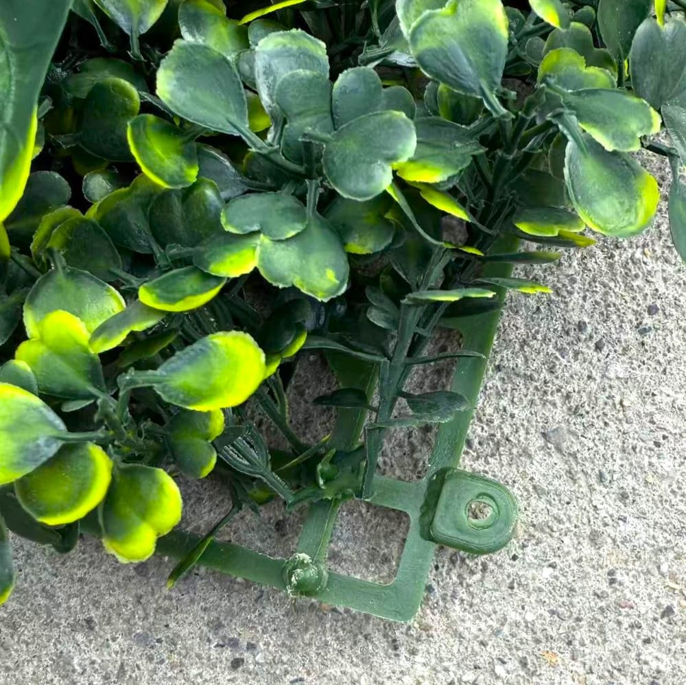 Interlocking artificial greenery wall panels being connected to form a seamless backdrop